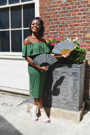 Victoria Ajoku holding 2 fans with the same print on different coloured sticks